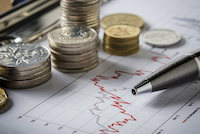 Coins and a pen resting on an investment chart