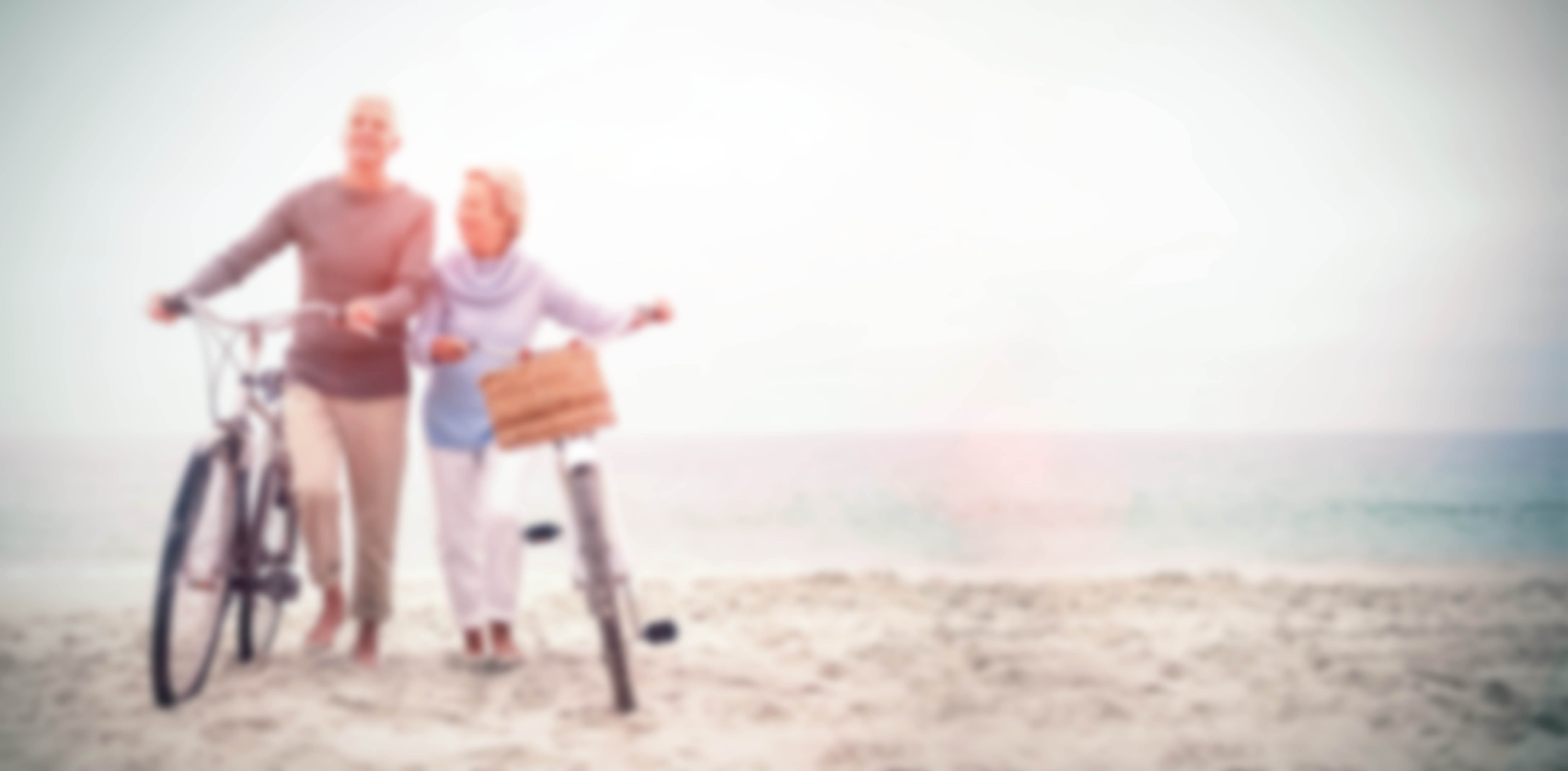 Retired couple walking with bicycles along a beach
