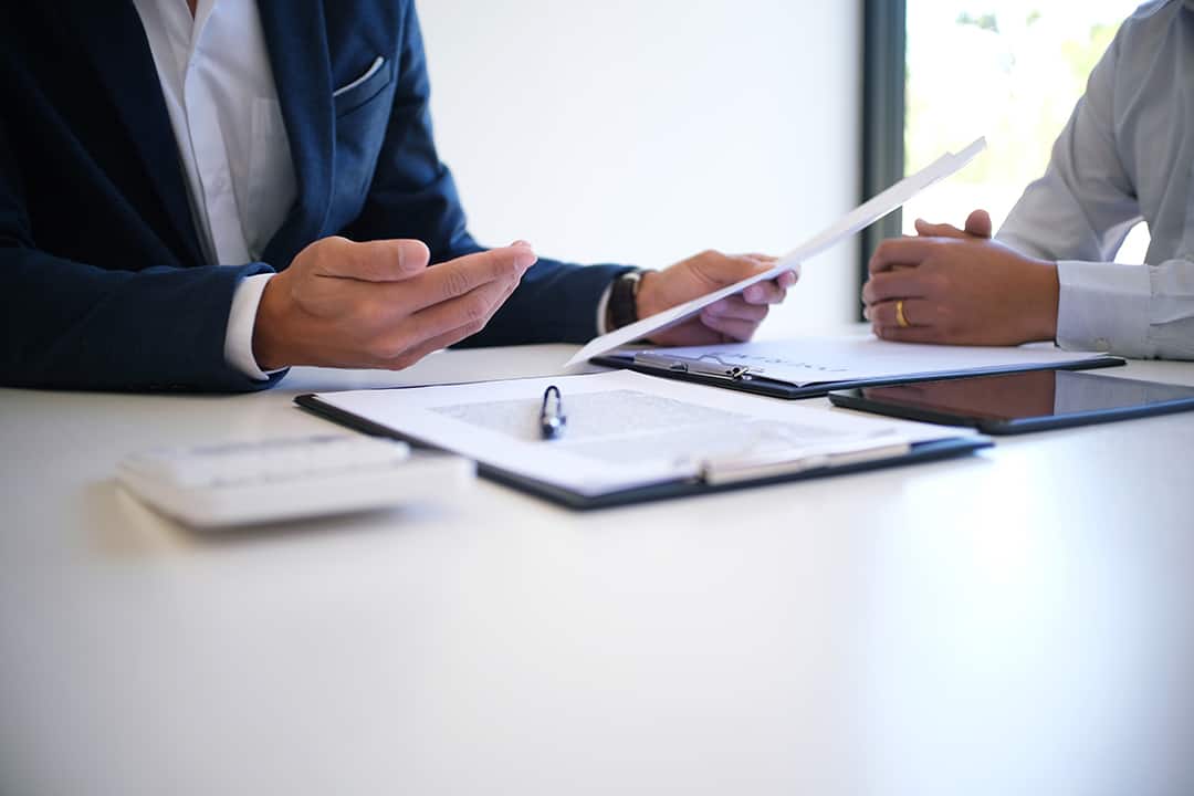 Advisor reviewing paperwork with a client at a meeting table